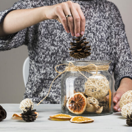 woman-hand-putting-pinecone-glass-jar