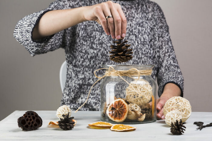 woman-hand-putting-pinecone-glass-jar